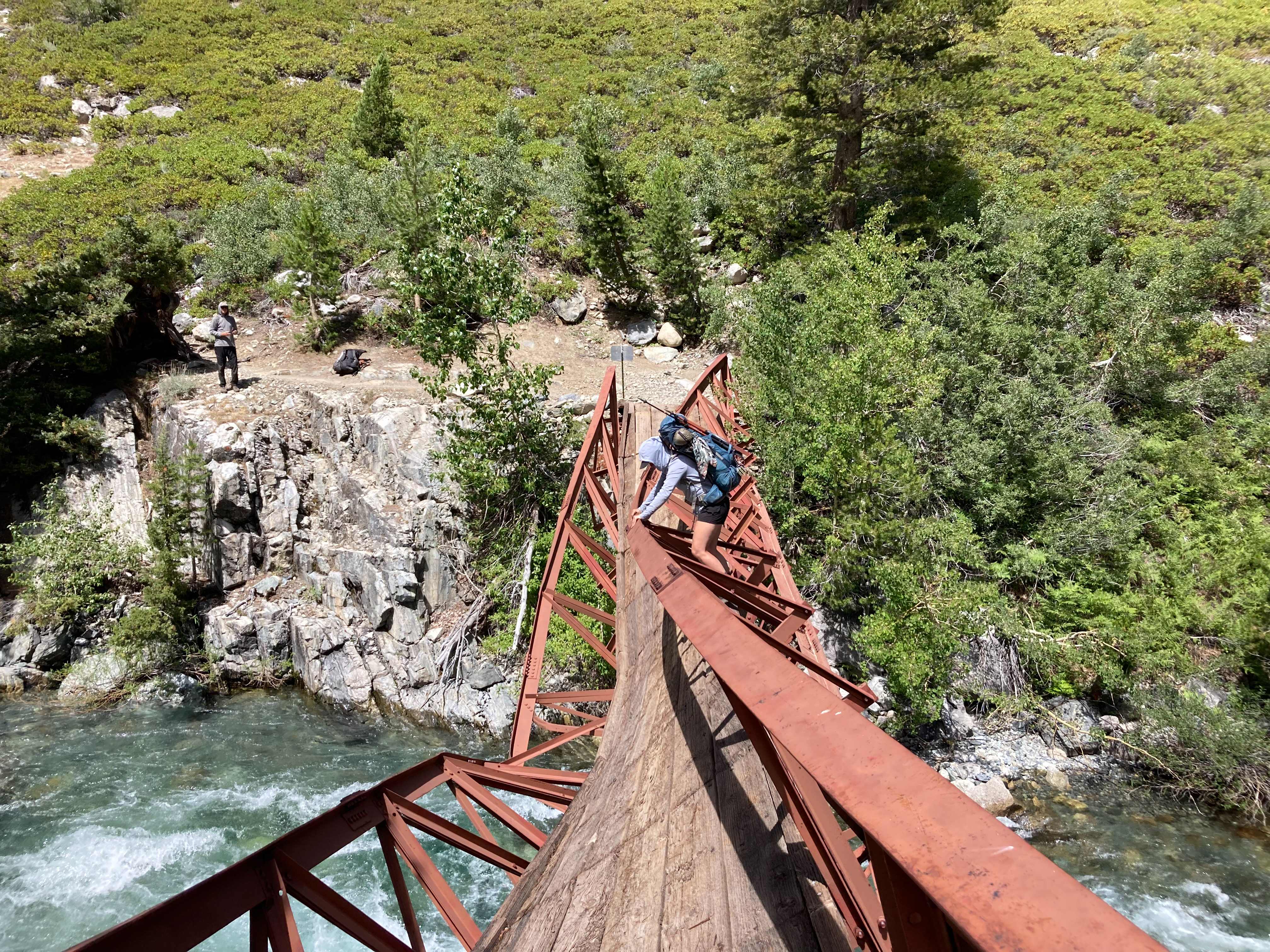 Sam Stych crossing the severely damaged San Joaquin bridge over the raging San Joaquin river in Kings Canyon National Park.